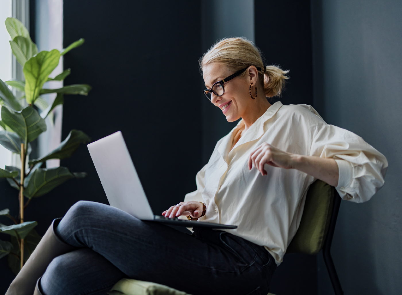 casually-dressed business woman on laptop, leaning back in chair