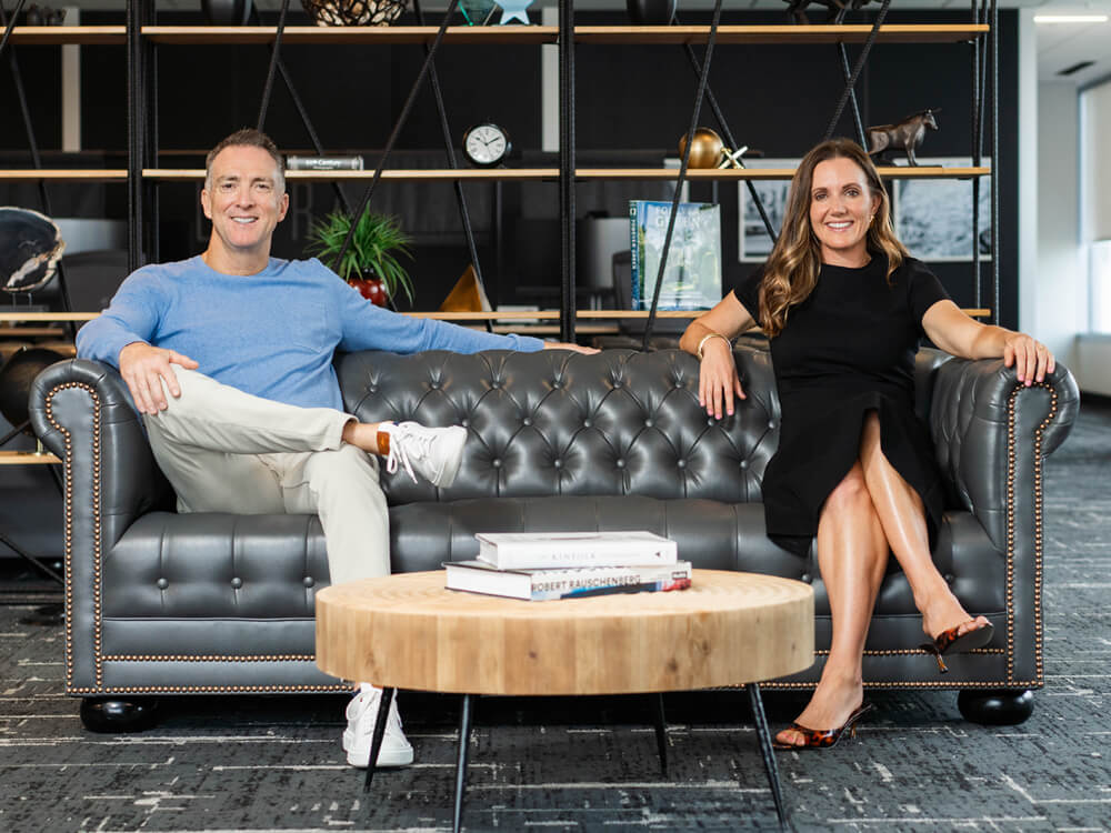 If You Could podcast hosts Matt Enyedi (left) and Taryn Huget (right) on host couch