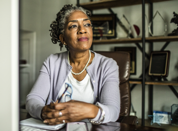 middle-aged african american woman looking to side sitting at table hands clasped