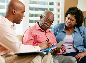 African American couple talking with business person in their home