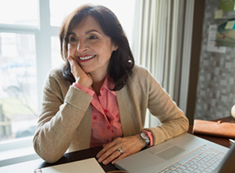 business woman smiling, hand on cheek, in front of laptop image