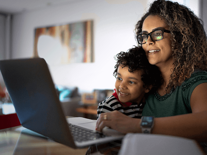 woman and child smiling at the laptop screen
