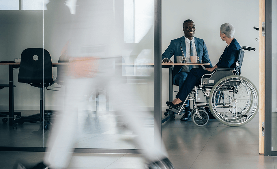 Man sitting at a desk talking to a woman in a wheelchair