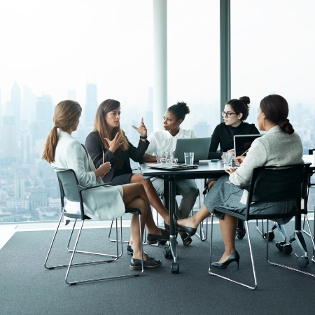 diverse group of business women sitting around table talking