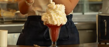 waitress putting more and more whipped cream on top of a sundae